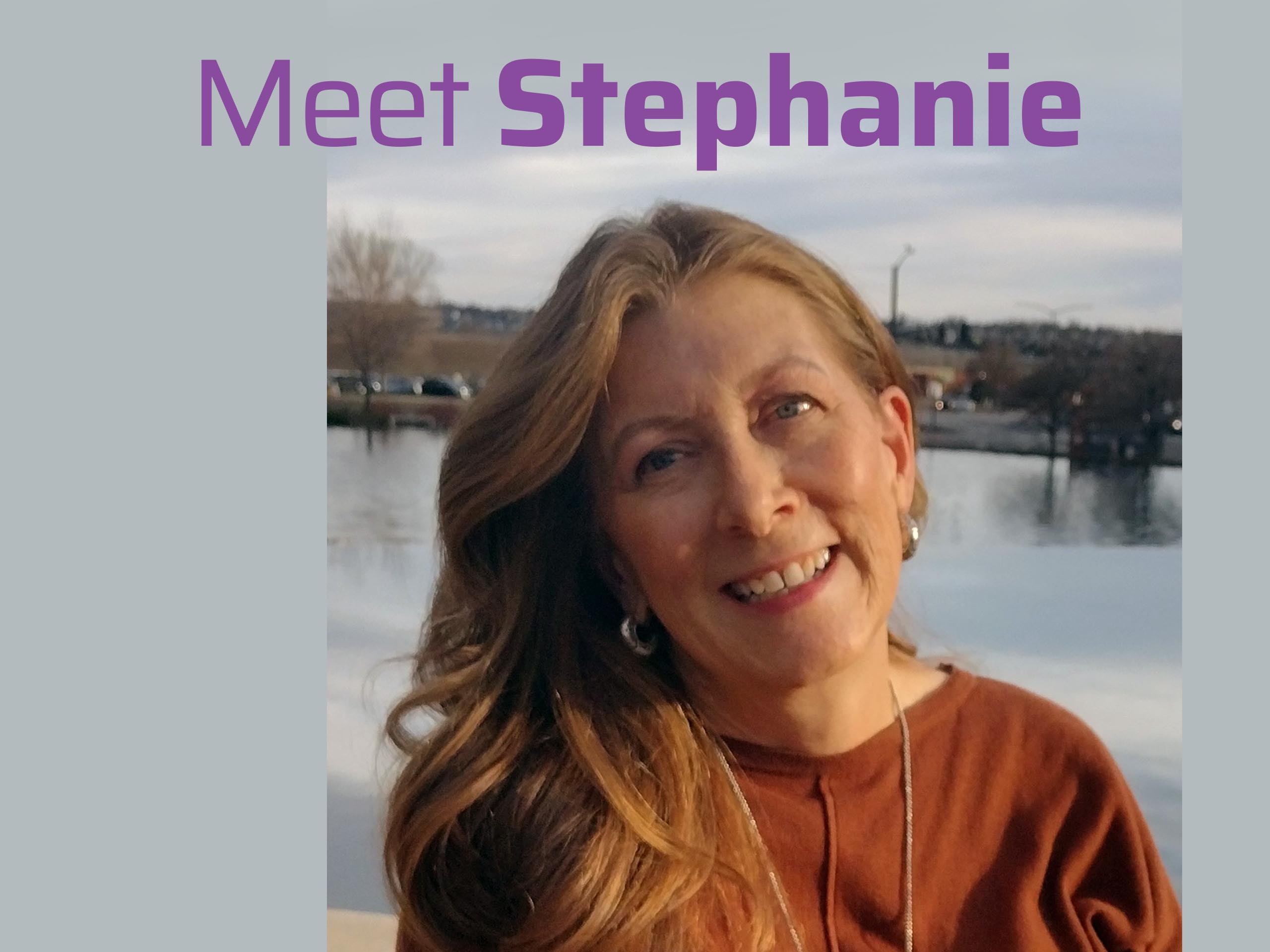 blonde woman standing in front of mountains and a lake.