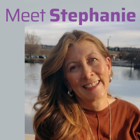 blonde woman standing in front of mountains and a lake.