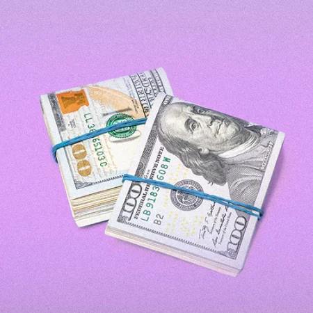 Folded hundred dollar bills on a light purple background.
