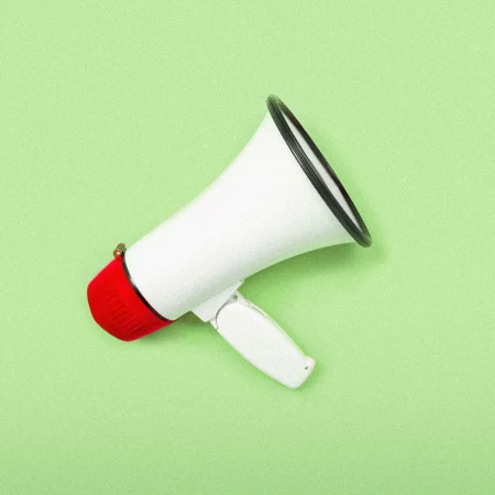 White and red bullhorn on a green background.